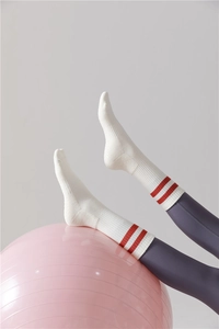 Détail de chaussettes de yoga en coton blanc à rayures rouges sur ballon rose