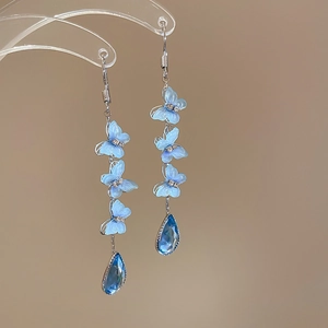 Detail of blue butterfly tassel earrings with teardrop crystal and silver finish