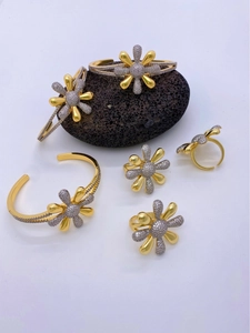 Detailed view of silver and gold daisy jewelry set with pavé zircon on black volcanic stone