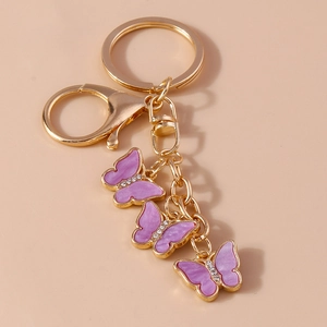 Macro detail of three purple butterfly charms with rhinestones on a gold keychain