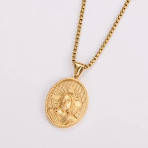 Macro shot of gold box chain and oval Jesus pendant necklace with embossed metal details