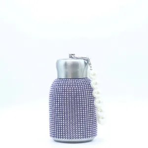 Detailed macro of a purple rhinestone water bottle with a white pearl carry handle strap