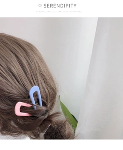 Detail of matte pink and blue U-shaped hairpins styled in a brown bun hairstyle