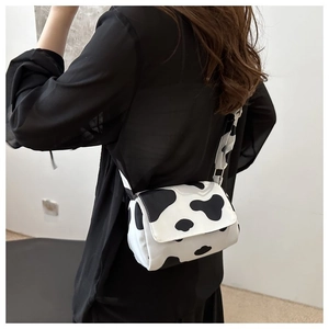 Close-up of trendy milk cow print crossbody bag with wide printed shoulder strap detail