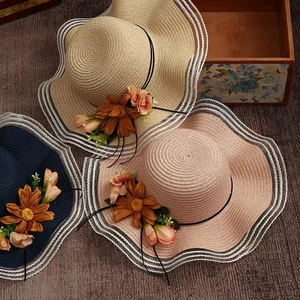 Wide brim straw sun hat with fabric flowers in navy blue, beige, and pink colors