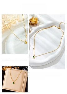 Detailed view of a gold chain necklace with a green teardrop-shaped pendant charm