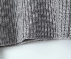 Détail de la texture en maille grise montrant les fils épais et les motifs de fibres douces