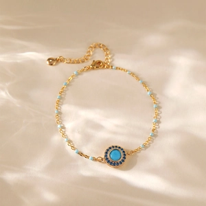 Bohemian gold chain bracelet with turquoise eye pendant on white silk fabric