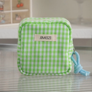 Detail of green and white plaid makeup pouch with blue rope zipper puller and label