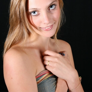 Model wearing a 3mm minimalist gold stainless steel ring and beaded bracelet on dark background