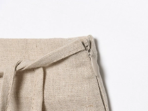 Macro detail of beige linen shorts featuring invisible zipper and belt loop craftsmanship