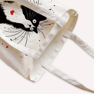 Off-white canvas tote bag featuring a cute cartoon cat print and sturdy carry handles