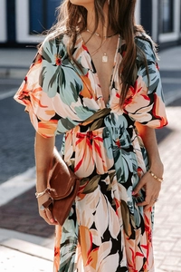 Detail of bohemian V-neck floral dress with waist tie and vibrant orange flower patterns