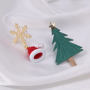 Detailed macro view of asymmetric Christmas earrings with enamel tree, hat, and pearl accents