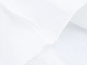 Gros plan détaillé montrant les coutures fines et la texture de dentelle blanche de la robe