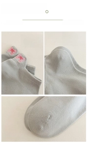 Detail of light grey cotton sock featuring pink bow embroidery and reinforced heel