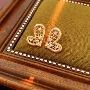 Macro shot of gold-plated heart earrings with hollow mesh and cubic zirconia