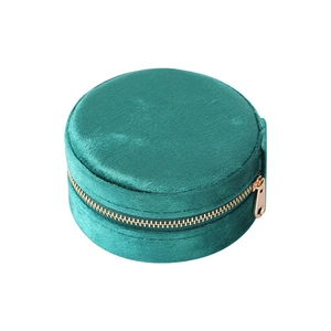 Circular emerald velvet jewelry travel case with a gold zipper closure and soft texture