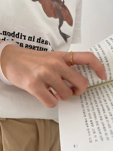 Delicate gold minimalist heart ring shown on hand while reading a book in lifestyle setting
