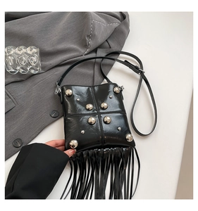 Close-up of black rivet handbag featuring long fringe tassels and polished PU leather