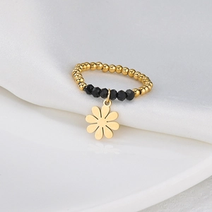 Detail of beaded stretch ring featuring golden petal charm and black faceted glass beads
