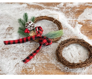 Close-up of natural grapevine Christmas wreaths with pine needles and plaid bows on snow