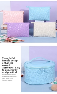 Close-up of heart-embossed patent leather makeup bags with large circular zip pullers
