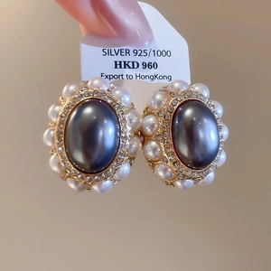 Macro detail of vintage oval black pearl earrings with S925 silver and crystal border