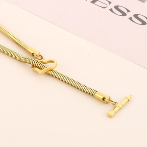 Close-up of golden flat snake chain necklace with heart pendant and toggle clasp