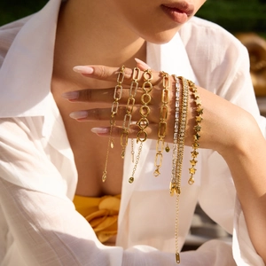 Gros plan de bracelets en acier inoxydable doré 18K avec breloques étoiles sur poignet