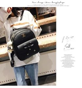 Detail view of black leather backpack with bow accent, gold logo plate, and cute bear charm