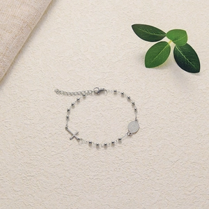 Detail of silver rosary bracelet with cross and Saint Benedict medal on natural background