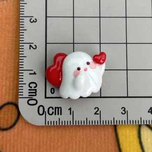 Detail showing white resin ghost charm with red heart and 2cm size measurement on a grid