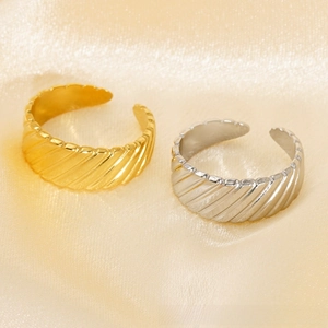 Detail of gold and silver plated croissant rings with twisted texture on silk background