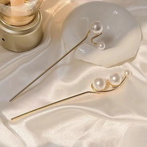 Elegant gold pearl hair pins on white silk background with soft lighting
