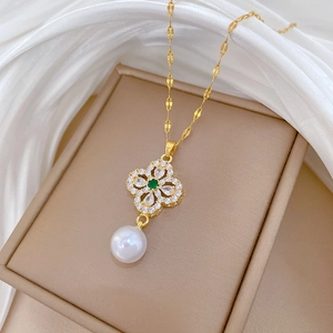 Detail of clover pendant with green center stone and white pearl on gold chain