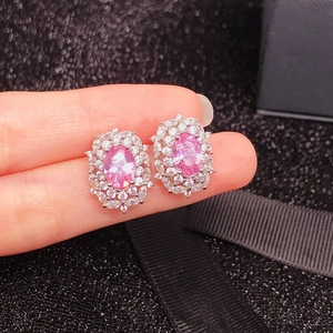 Macro shot of oval pink gemstone earrings with sparkling white halo setting in silver