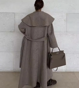 Back view of long brown camel wool coat with waist tie and matching leather handbag