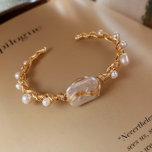 Macro detail of handmade wire-wrapped gold bracelet with Baroque and round pearls