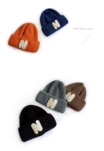 Flat lay of colorful knitted beanie hats for kids featuring distinct N-letter patches