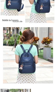 Detail of blue waterproof nylon backpack with zipper pockets and a cute bear charm