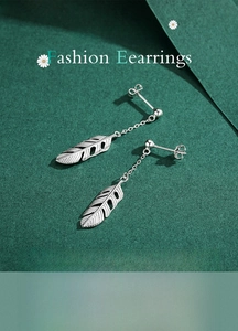 Macro detail of silver feather drop earrings showing delicate texture and fine chain