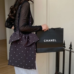 Detail of black floral tote bag featuring elegant ruffle bow design and large capacity