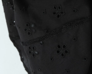 Gros plan détaillé de la broderie florale complexe et des coutures fines sur une robe noire en V