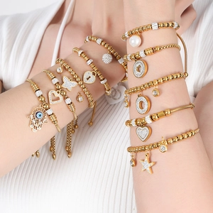 Layered 18K gold-plated beaded bracelets featuring hamsa hand, heart and pearl charms