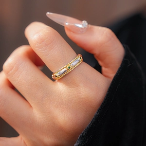 Detail of vintage two-tone braided ring with green gemstone inlay on finger