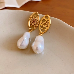 Macro detail of gold hollow-out flower and Love design with baroque pearls
