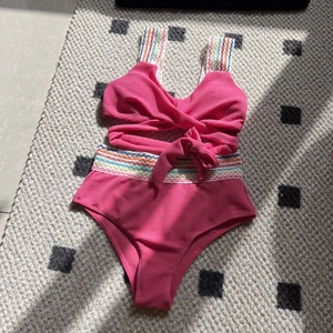 Detail of high waisted rose pink bikini featuring rainbow wave embroidery and honeycomb fabric
