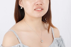 Close-up of grey shell pearl necklace and matching earrings set worn by a model