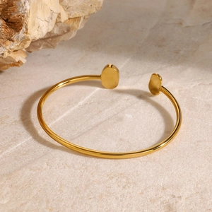 Minimalist gold-plated stainless steel open bangle with pearl on stone background
